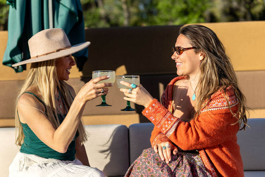 Friends enjoying margaritas from The Den while sitting poolside at Mountain Modern Sedona