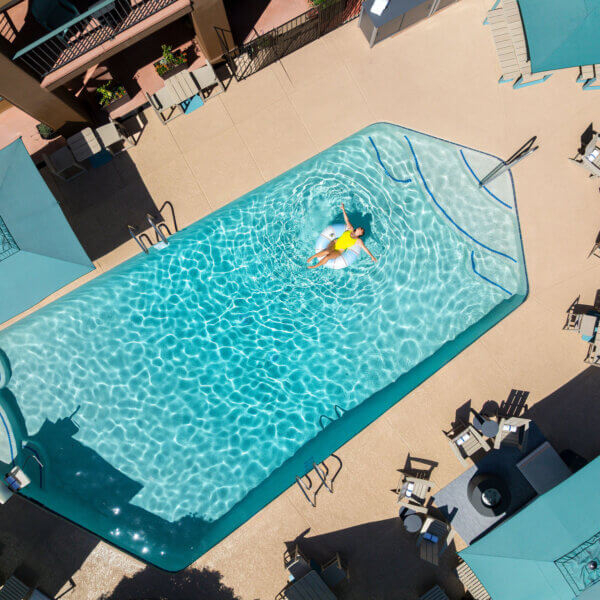 Woman floating in pool in yellow bathing suit enjoying the sun.